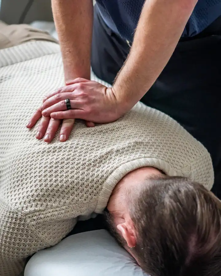 Eine Behandlerin behandelt Rücken und Nacken eines Patienten