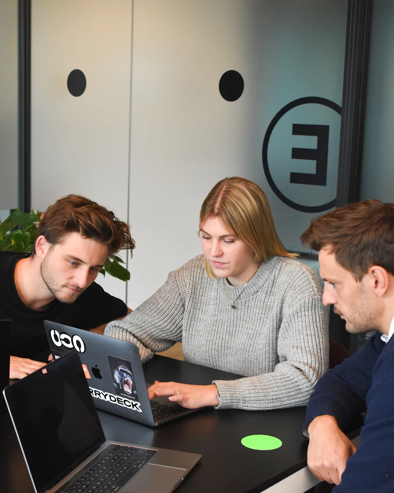 Drei Menschen arbeiten gemeinsam an einem Laptop im Büro