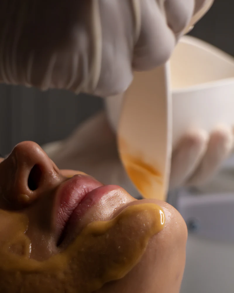 Eine Kosmetikerin trägt einer Kundin eine Gesichtsmaske auf